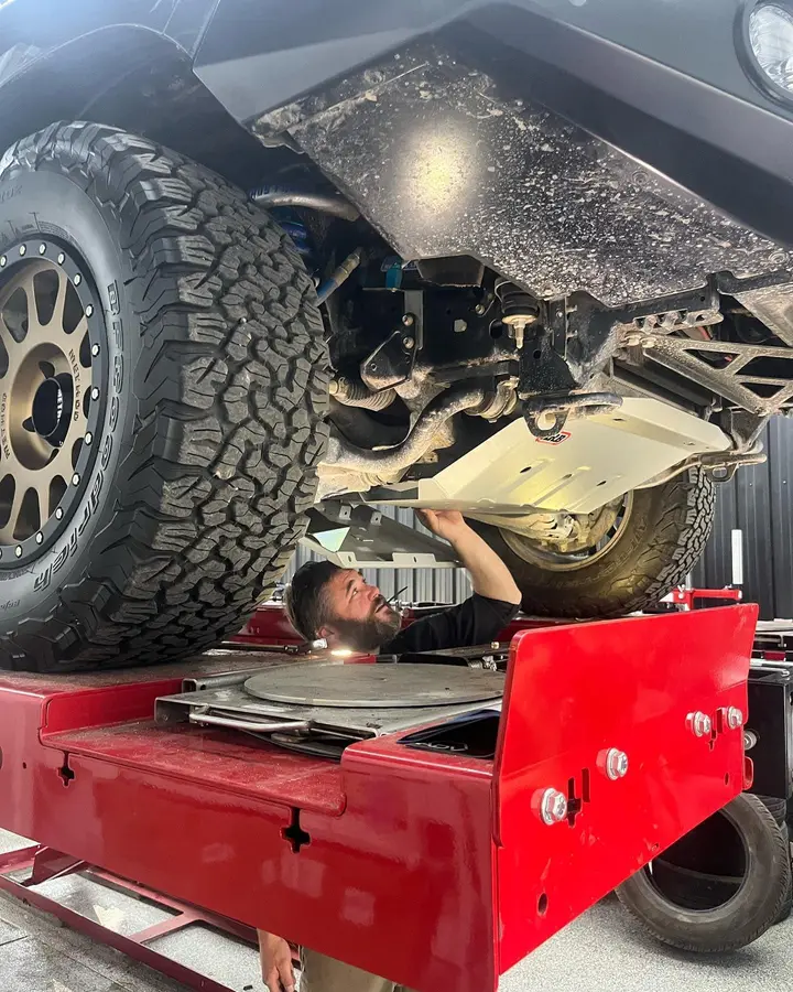 Technician on alignment rack working under vehicle