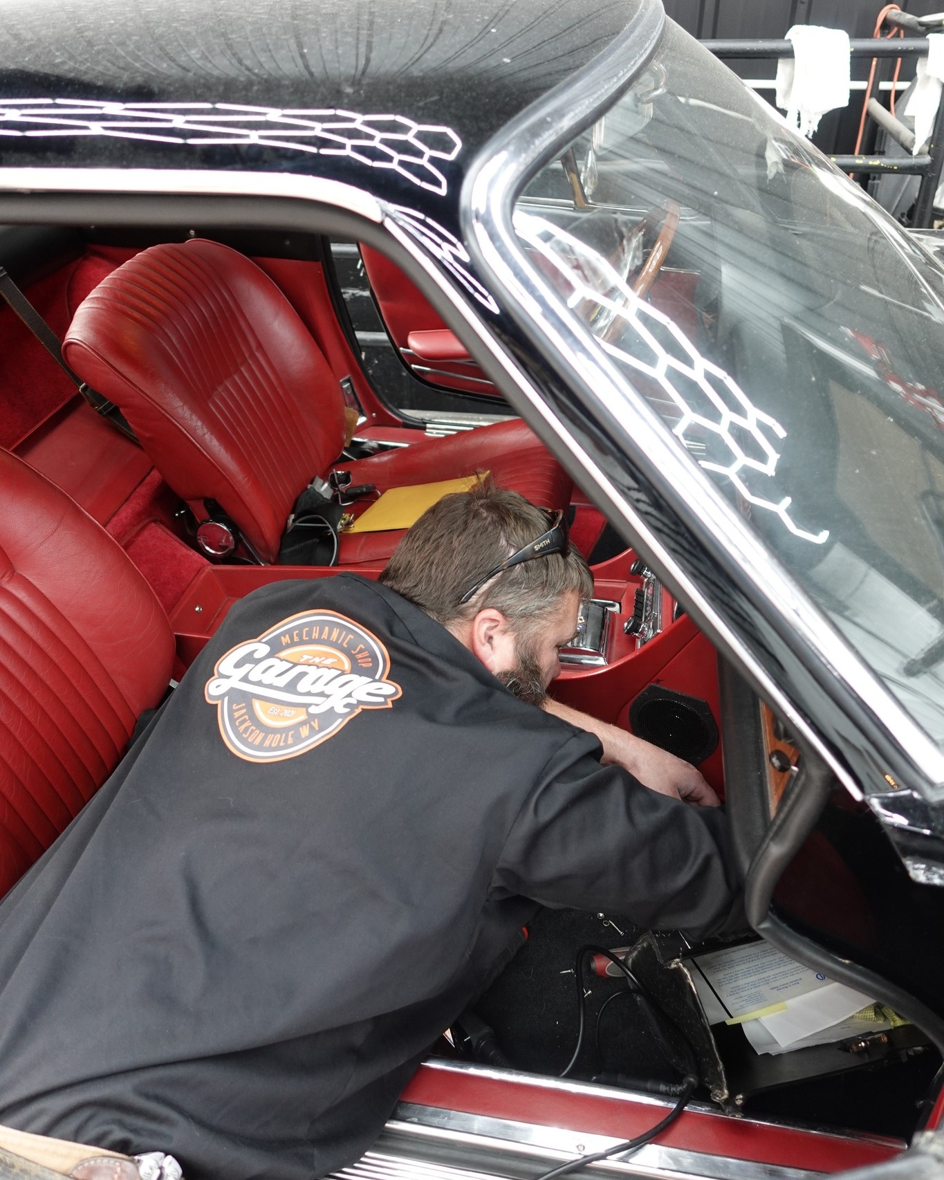 Technician repairing the interior of a classic car with red leather seats