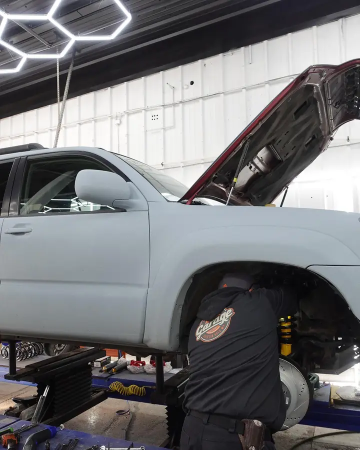 The Garage technician performing suspension and brake work on a lifted SUV