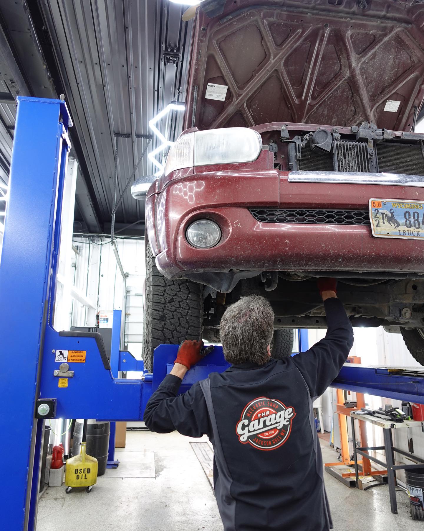 Technician working beneath a lifted SUV inside The Garage service bay